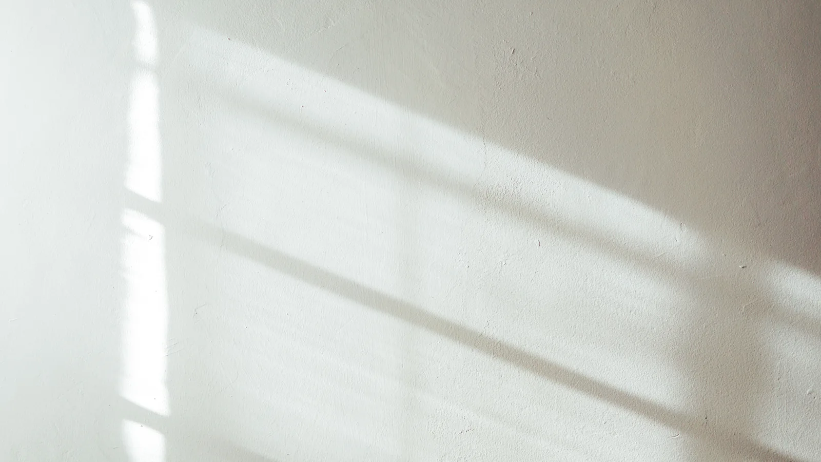 Daylight raking across a smooth finished wall, the light that shows every seam